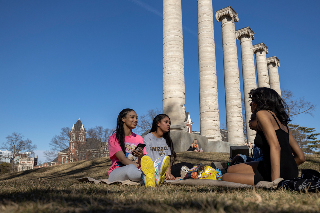 Students sit by the columns.